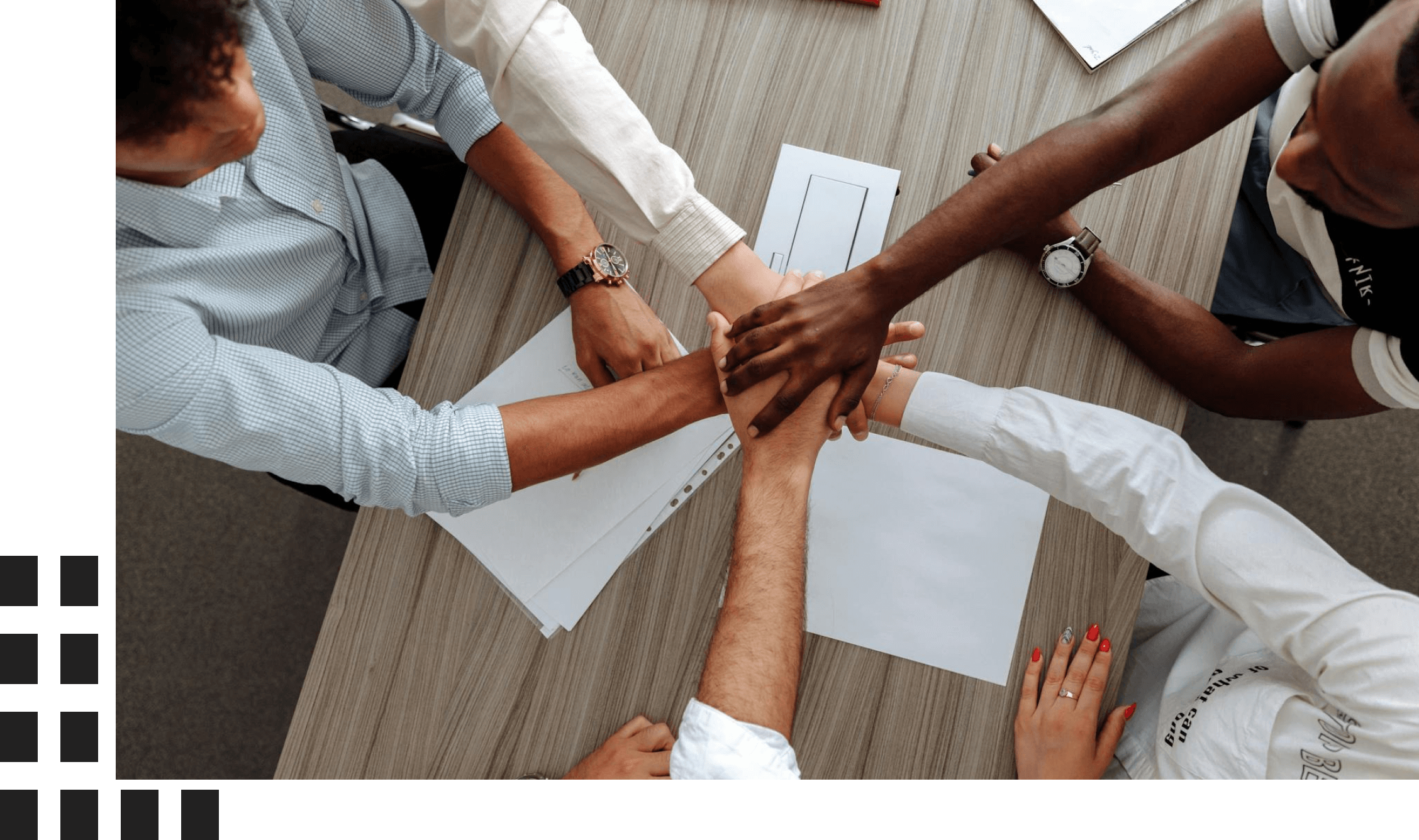 Diverse team joining hands over a table in a collaborative effort