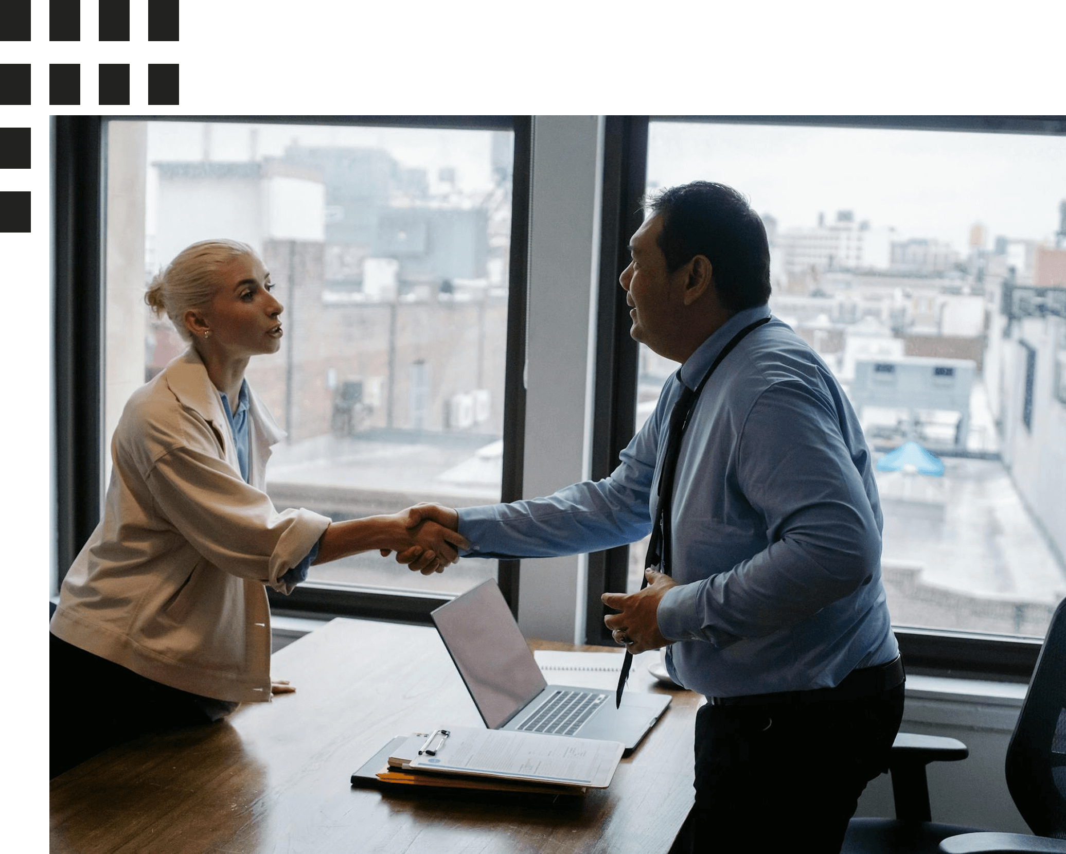Business professionals shaking hands in a modern office with a city view